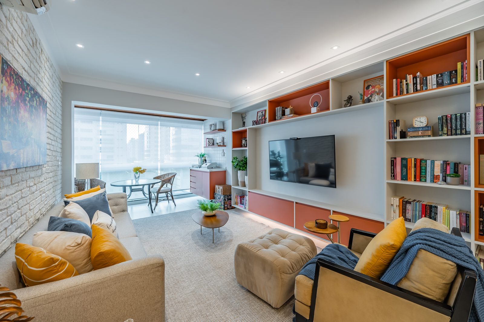 Sala de estar com parede de tijolos brancos e estante planejada — apartamento reformado Santos