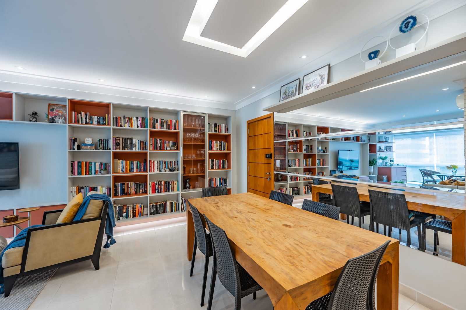 Sala de jantar integrada com mesa de madeira maciça e estante — reforma residencial