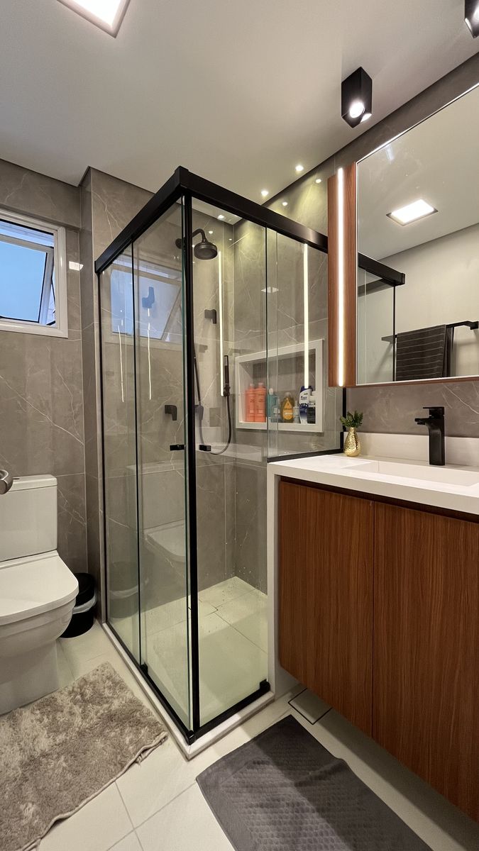 Banheiro moderno com porcelanato cinza e box de vidro preto — reforma residencial